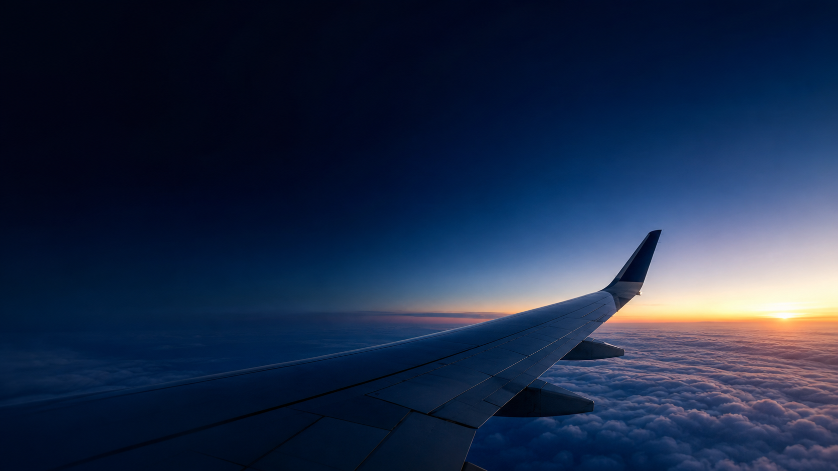 Aircraft wing above clouds at sunrise
